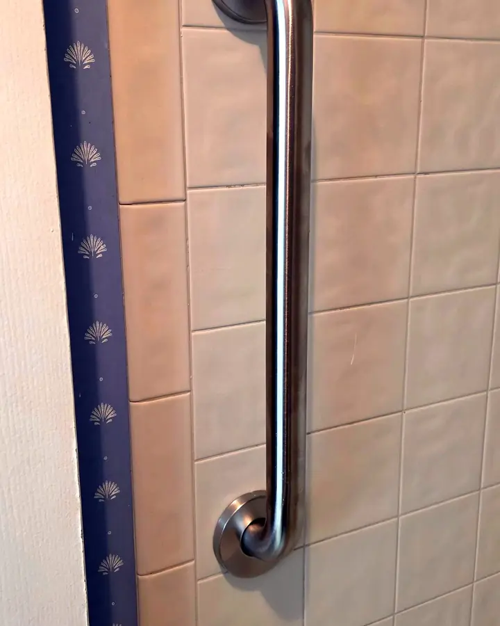 Vertical stainless grab bar at a shower entry on tile, Longwood